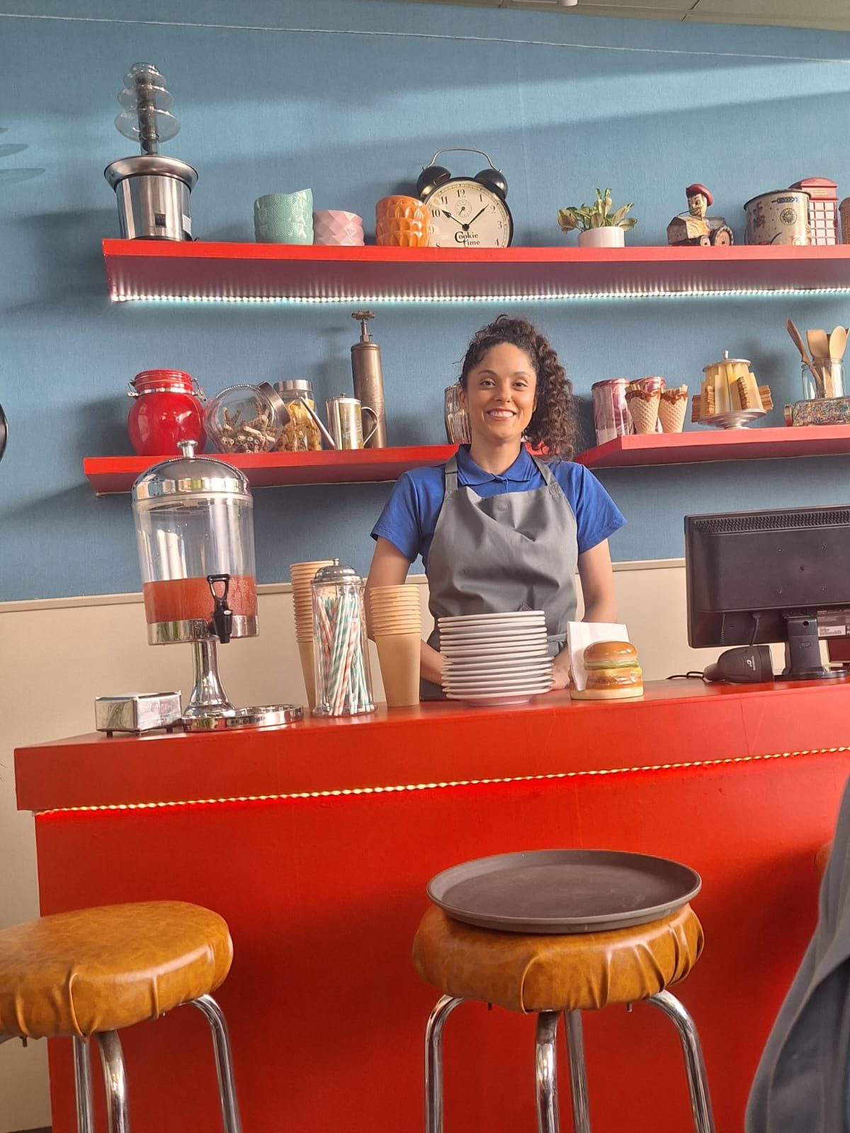 Amanda como garçonete em cenário de lanchonete de comercial