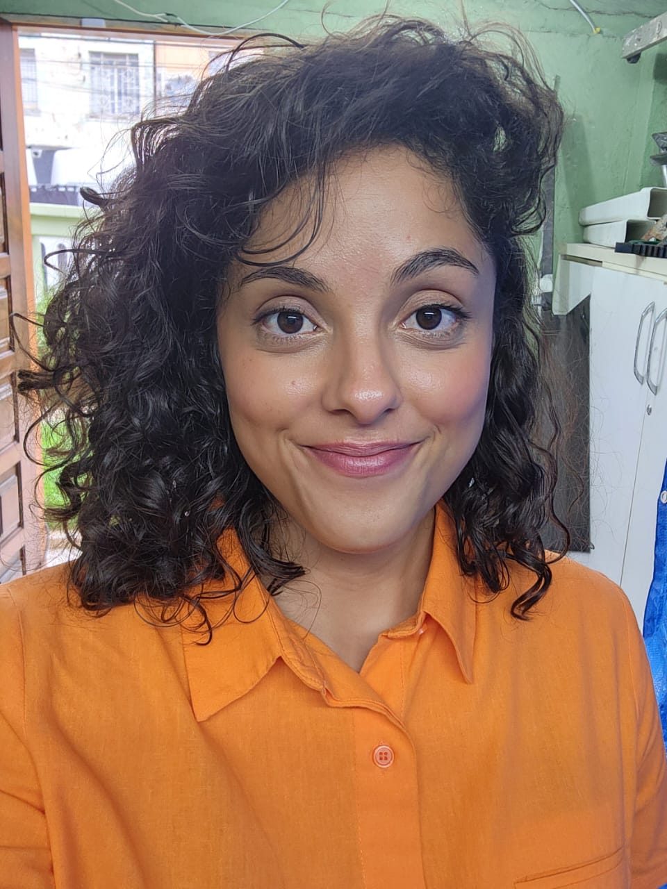 Retrato de Amanda de camisa laranja, cabelo cacheado